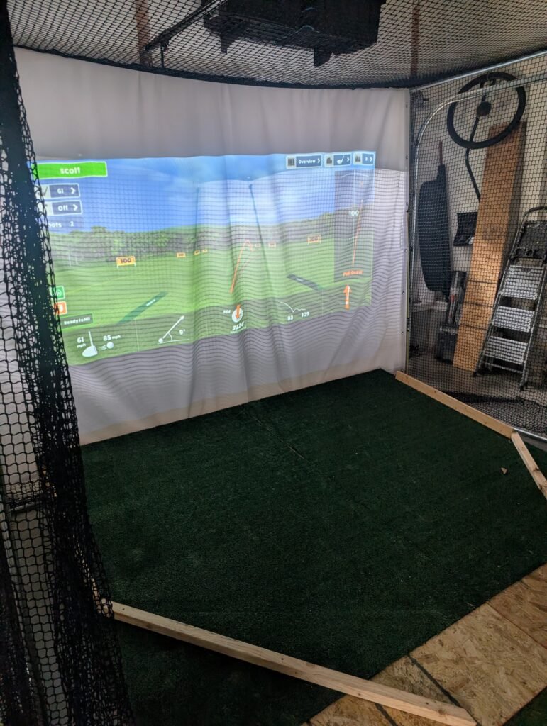 Impact screen and hitting net installed in a DIY golf simulator enclosure