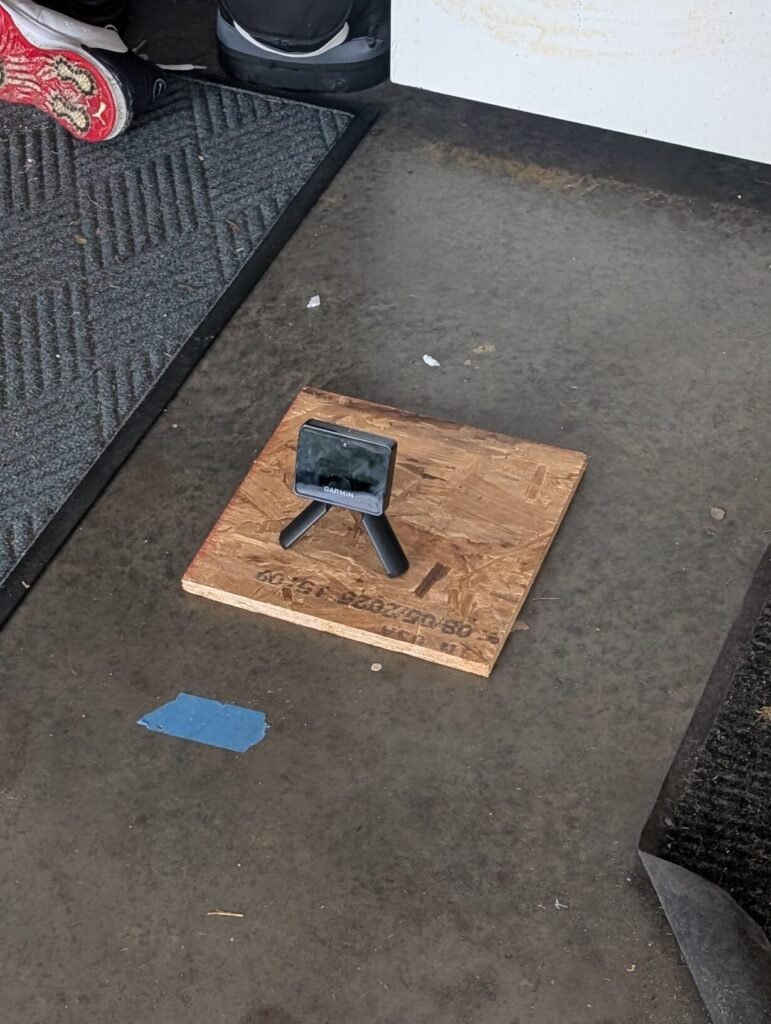 Garmin R10 launch monitor positioned behind the hitting area in a DIY golf simulator setup